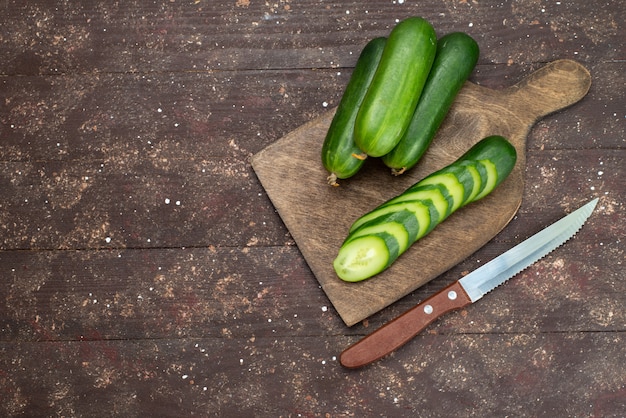 Bovenaanzicht verse groene komkommers geheel en gesneden op donker