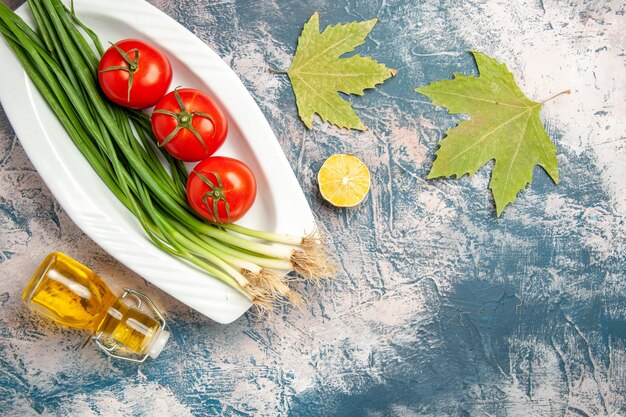 Bovenaanzicht verse groene ui met tomaten op de lichtblauwe achtergrond