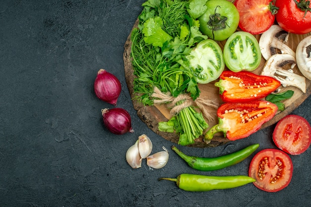 Bovenaanzicht verse groenten champignons rode en groene tomaten paprika greens op rustieke bord