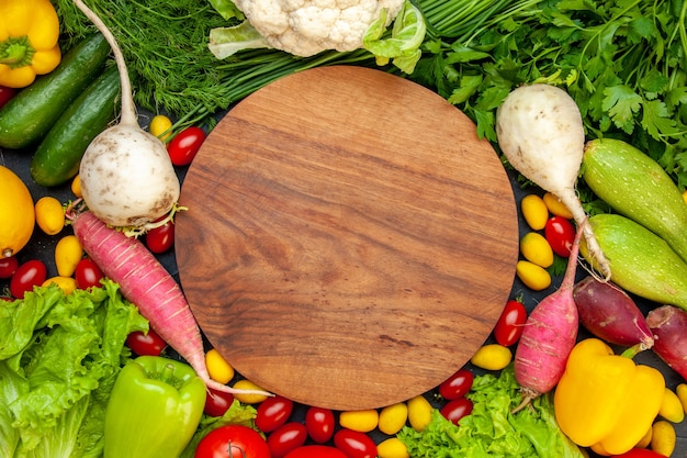 Bovenaanzicht verse groenten cherrytomaatjes cumcuat sla dille gele paprika komkommer courgette ronde houten bord in het midden