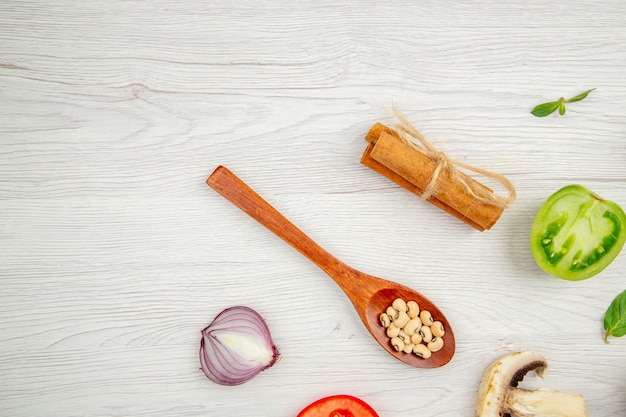 Bovenaanzicht verse groenten houten lepel paddestoel muntblaadjes knoflook kaneelstokjes op grijze tafel