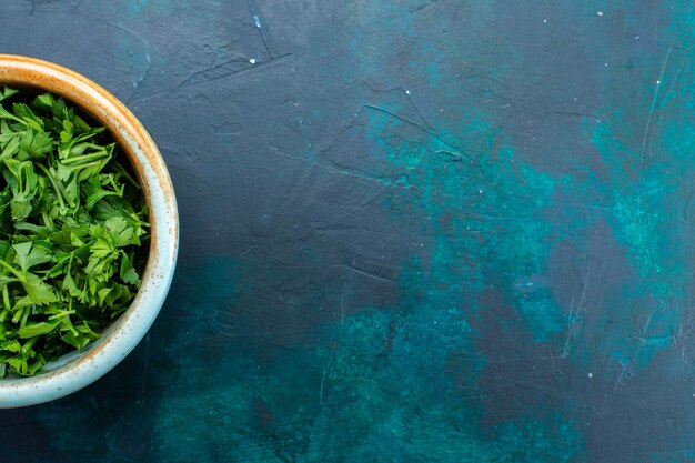 Bovenaanzicht verse groenten in ronde pot op het donkerblauwe bureau.