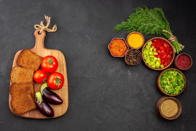 Bovenaanzicht verse groenten met donkere broodbroden en kruiden op het donkere oppervlak salade maaltijd brood eten