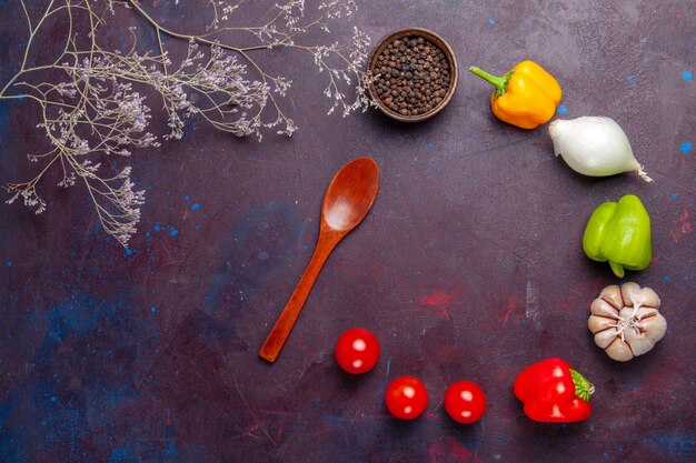 Bovenaanzicht verse groenten met peper op donkere ondergrond plantaardige maaltijd voedsel kruiden ingrediënt