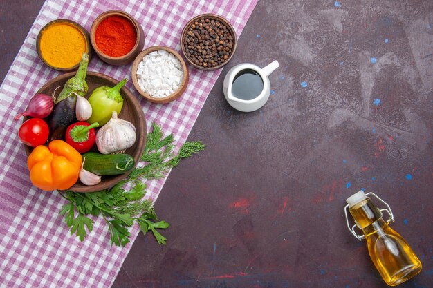 Bovenaanzicht verse groenten met smaakmakers op het donkere oppervlak rijpe salade eten gezondheidslunch