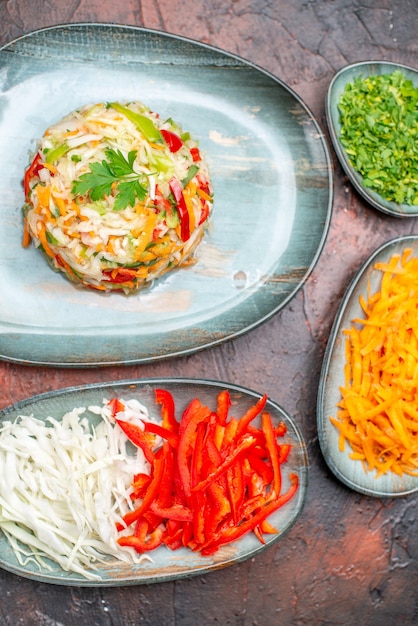 Bovenaanzicht verse groentesalade met gesneden wortelkool en paprika op de donkere tafel