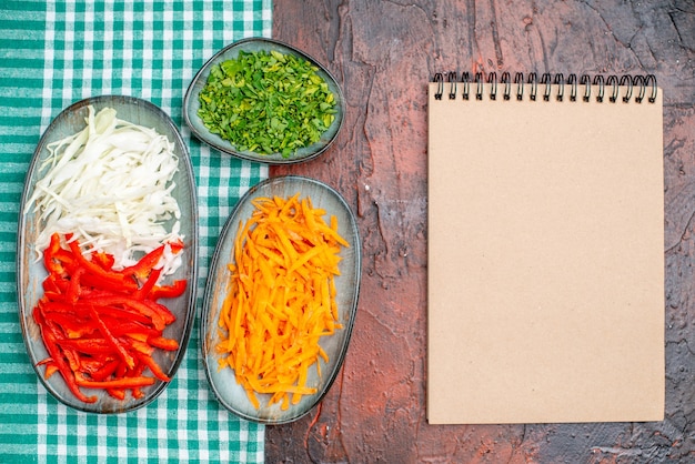 Bovenaanzicht verse groentesalade met greens en gesneden groenten op donkere tafel