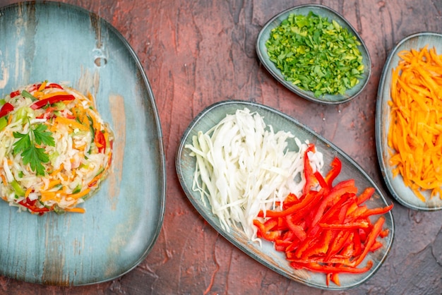 Bovenaanzicht verse groentesalade met greens en gesneden groenten op donkere tafel