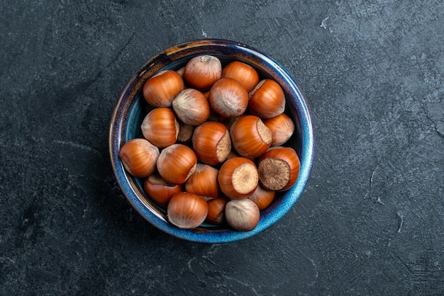Bovenaanzicht verse hazelnoten in kleine pot op donkere ondergrond noot hazelnoot walnoot snack pinda