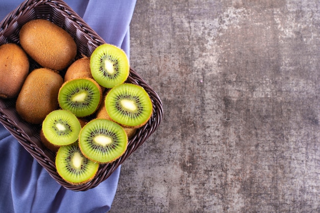 Bovenaanzicht verse heerlijke kiwi in mand met kopie ruimte op paarse doek