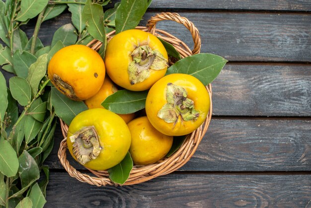 Bovenaanzicht verse kaki in mand op de houten tafel, fruit mellow rijp