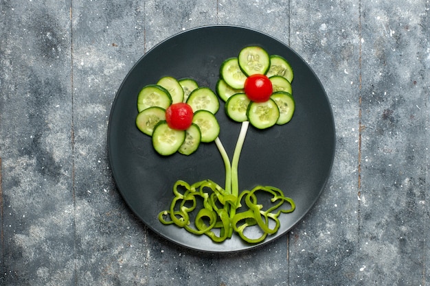 Bovenaanzicht verse komkommers bloem ontworpen salade op grijze ruimte