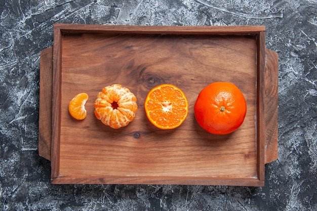 Bovenaanzicht verse mandarijnen gepelde mandarijnen op houten dienblad op grijze tafel