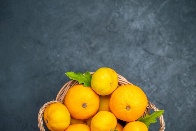 Bovenaanzicht verse mandarijnen in rieten mand op donkere achtergrond