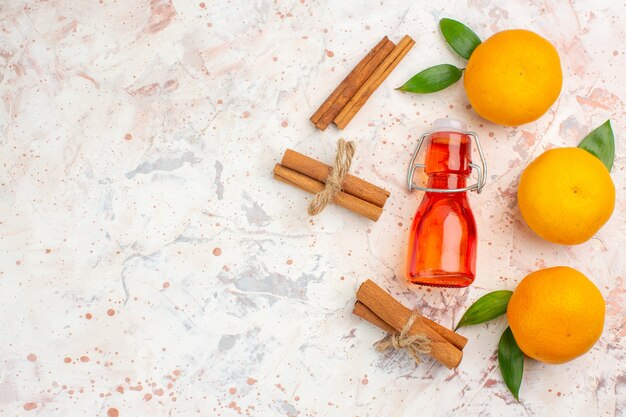 Bovenaanzicht verse mandarijnen kaneelstokjes fles op lichte oppervlak vrije plaats