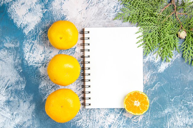 Bovenaanzicht verse mandarijnen met notitieblok op lichtblauwe achtergrond