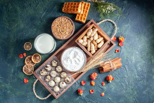 Bovenaanzicht verse melk met noten en eieren op donkerblauwe achtergrond bak cake biscuit taart thee deeg broodje gebak suiker