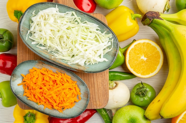 Bovenaanzicht verse paprika met gesneden kool bananen appels en sinaasappel op witte achtergrond foto salade gezond leven rijp kleur dieet