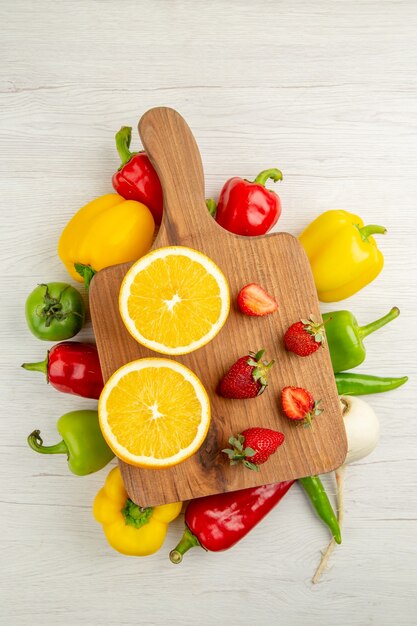 Bovenaanzicht verse paprika met gesneden sinaasappel en aardbeien op witte achtergrond salade rijpe kleurenfoto gezond leven dieet