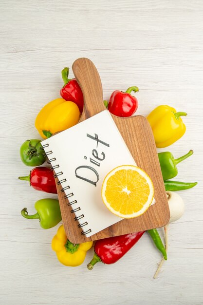 Bovenaanzicht verse paprika met gesneden sinaasappel op witte achtergrond salade rijpe kleur gezond leven dieet foto