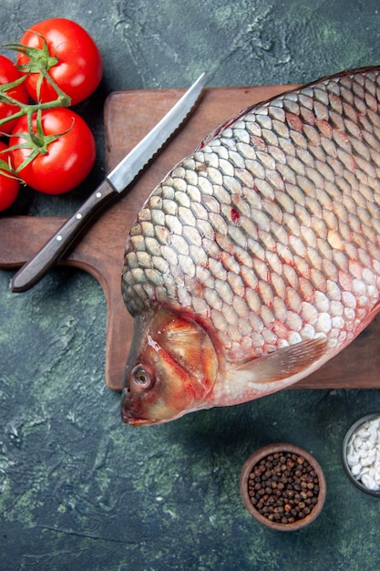 Bovenaanzicht verse rauwe vis op snijplank met tomaten donkerblauwe achtergrond