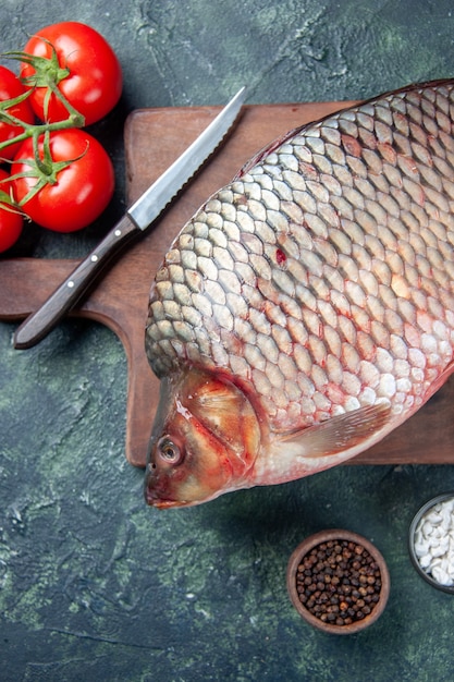 bovenaanzicht verse rauwe vis op snijplank met tomaten donkerblauwe achtergrond