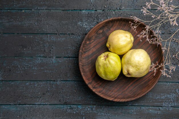 Bovenaanzicht verse rijpe kweeperen zure vruchten in plaat op donkerblauwe rustieke bureauplant fruit rijpe verse boom