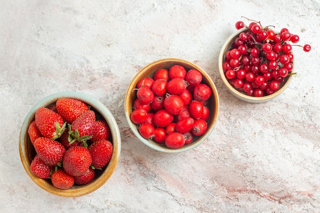 Bovenaanzicht verse rode aardbeien met ander fruit op witte tafel, fruitbes
