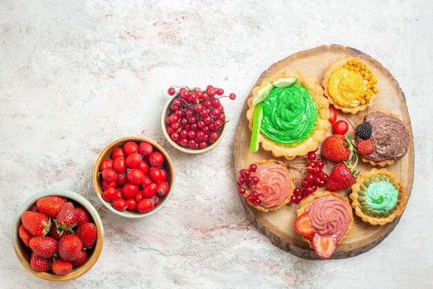 Bovenaanzicht verse rode aardbeien met fruit en gebak op witte tafel fruitbes