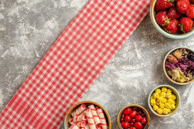 Bovenaanzicht verse rode aardbeien met snoepjes op wit oppervlak bessen vers snoep fruit