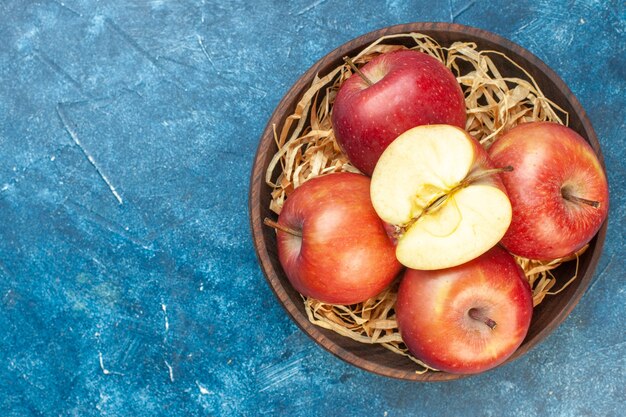 Bovenaanzicht verse rode appels binnen plaat op blauwe tafel