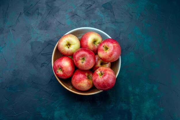 Bovenaanzicht verse rode appels sappig en zacht binnen plaat op het donkerblauwe bureau fruit verse rijpe zachte vitamine