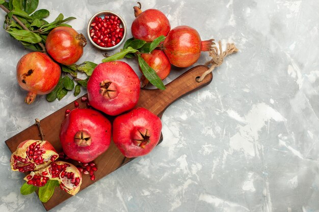 Bovenaanzicht verse rode granaatappels zuur en zacht fruit op het lichtwitte bureau