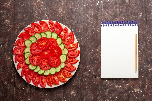 Gratis foto bovenaanzicht verse rode tomaten gesneden verse salade op bruin bureau