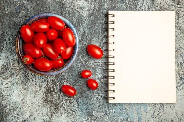 Bovenaanzicht verse rode tomaten met blocnote op donker-lichttafel fruitfoto donkere salade