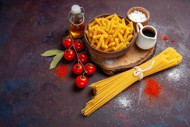 Bovenaanzicht verse rode tomaten met rauwe Italiaanse pasta op donkere bureau rauwe salade pasta eten maaltijd