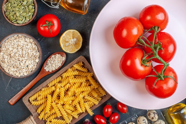 Gratis foto bovenaanzicht verse rode tomaten met rauwe pasta groenten kruiderijen en eieren op een donkere achtergrond kleur olie calorie voedsel ei melk deeg diner maaltijd