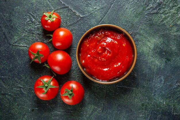 Bovenaanzicht verse rode tomaten met tomatenpuree op donkere ondergrond