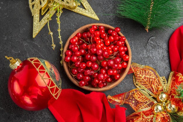 Bovenaanzicht verse rode veenbessen rond kerstspeelgoed op een donkere achtergrond