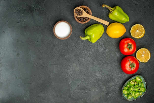 Bovenaanzicht verse tomaten met paprika en citroen op donkere achtergrond