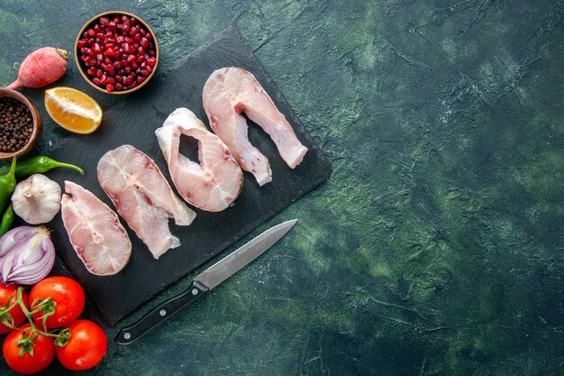 Bovenaanzicht verse vis plakjes met rode tomaten op donkerblauwe achtergrond oceaan vlees zeevruchten peper schotel voedsel zeemeel water