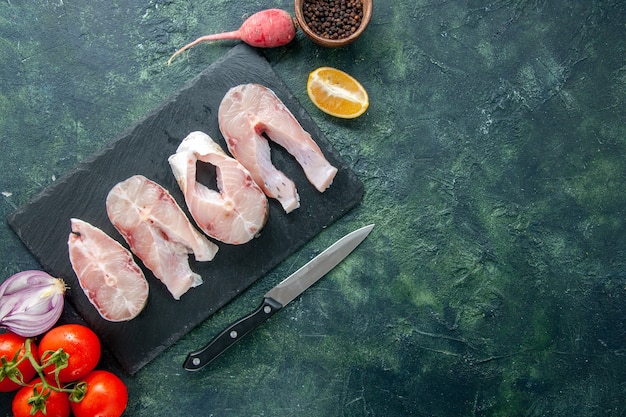 Bovenaanzicht verse vis plakjes met rode tomaten op donkerblauwe achtergrond oceaan vlees zeevruchten voedsel peper water schotel zee maaltijd