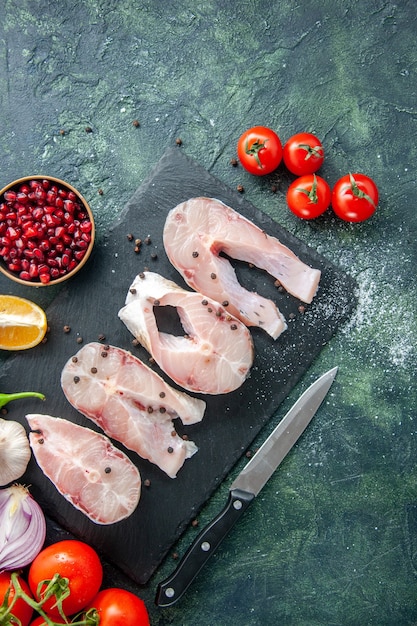 Bovenaanzicht verse vis plakjes met rode tomaten op een donkerblauwe tafel oceaan vlees zeevruchten peper schotel zeemeel water voedsel