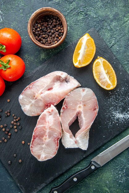 Bovenaanzicht verse vis plakjes met rode tomaten op het donkerblauwe oppervlak oceaan vlees zeevruchten zeevruchten zeevruchten voedsel peper water schotel