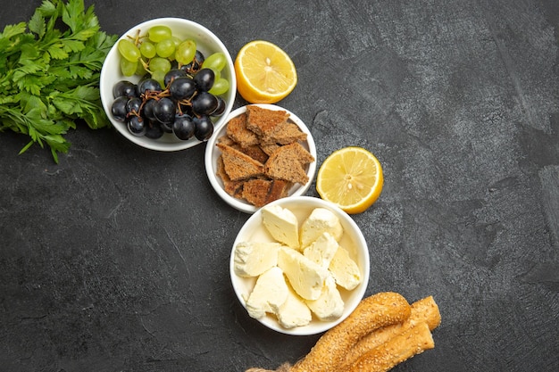 Gratis foto bovenaanzicht verse zachte druiven met witte kaas greens en gesneden brood op donkere oppervlakte maaltijd voedsel melk fruit