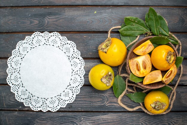 Gratis foto bovenaanzicht verse zoete kaki op houten rustieke tafel, proef rijp fruit