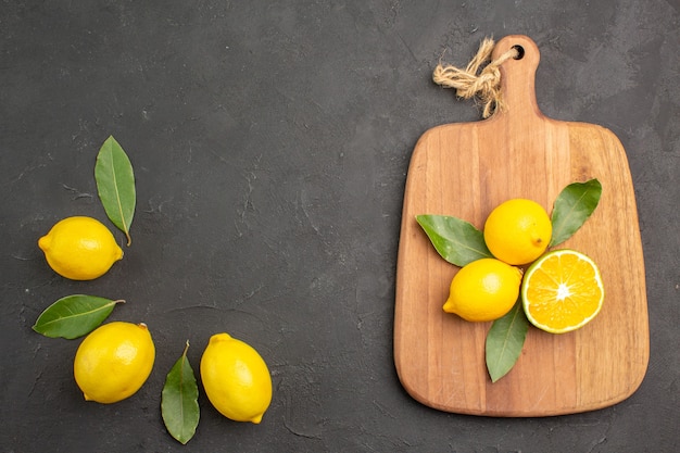 Bovenaanzicht verse zure citroenen met bladeren op de donkere tafel fruit limoen gele citrus