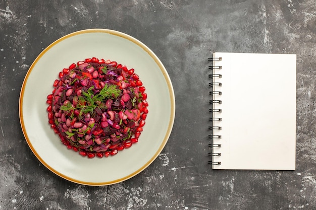 Gratis foto bovenaanzicht vinaigrette salade met granaatappels en bonen op grijs bureau