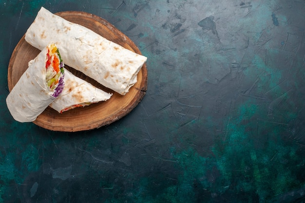 Bovenaanzicht vlees sandwich een sandwich gemaakt van vlees gegrild aan het spit met groenten op het donkerblauwe bureau sandwich hamburger eten maaltijd lunch vlees foto