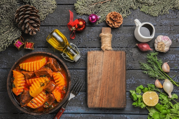 Bovenaanzicht vlezige soep met greens en aardappelen op het donkere bureau